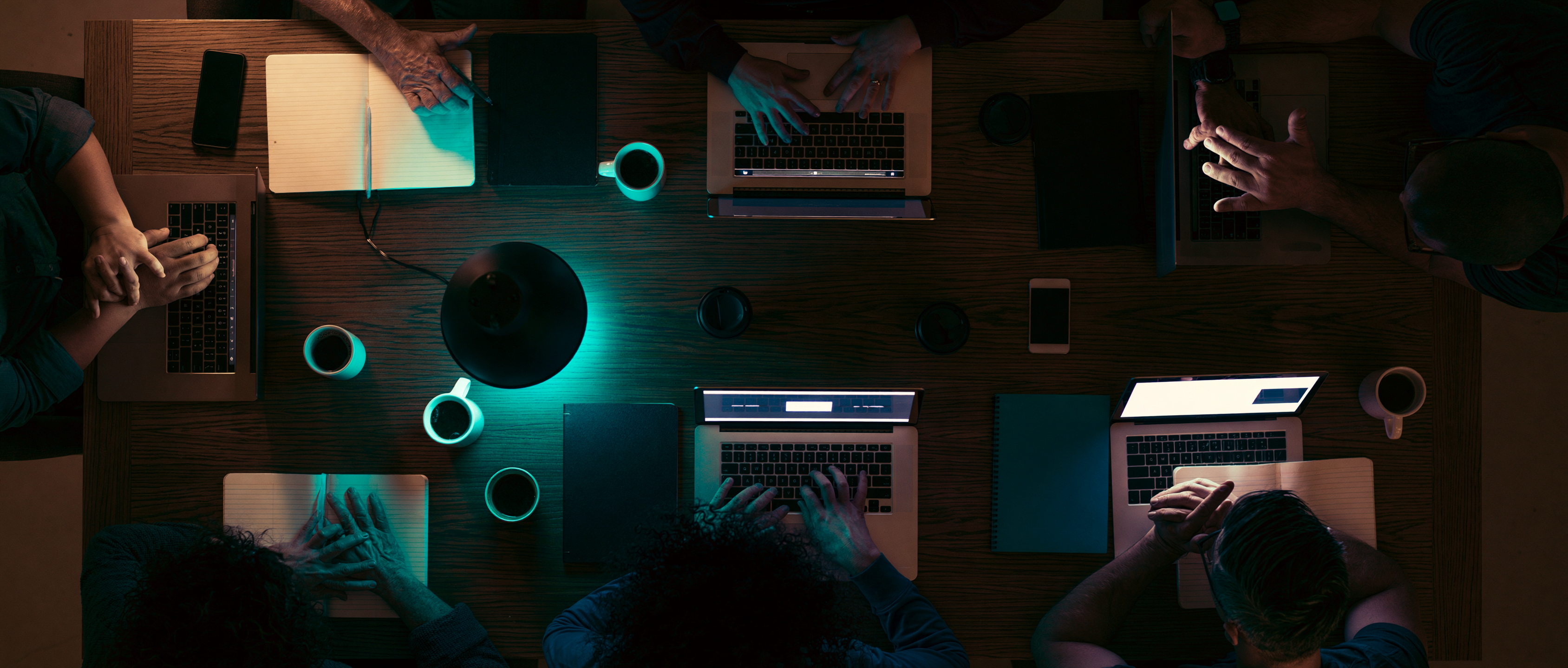A team working late around one table, lit by a single lamp